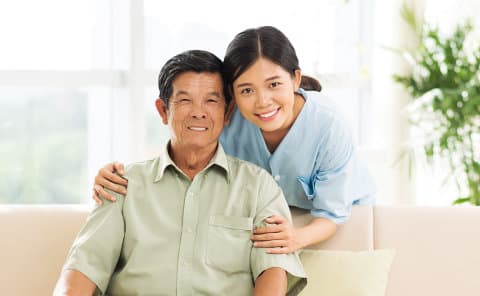 caregiver and senior man on couch smiling