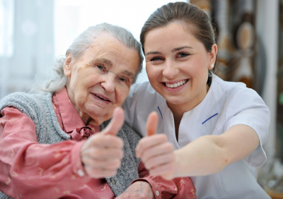 senior woman and a caregiver doing thumbs up